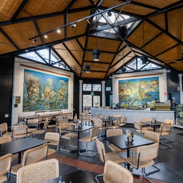 A modern café with wicker chairs and black tables.