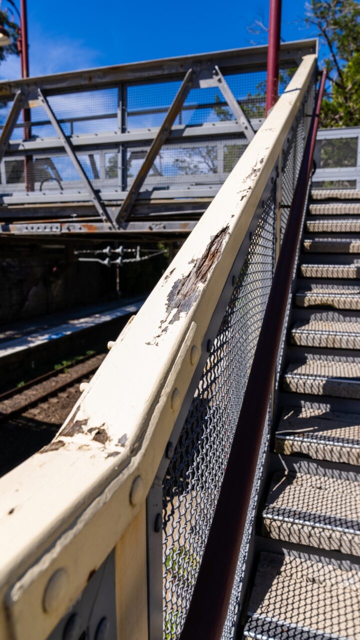 Close-up of a metal staircase with peeling paint on the handrail