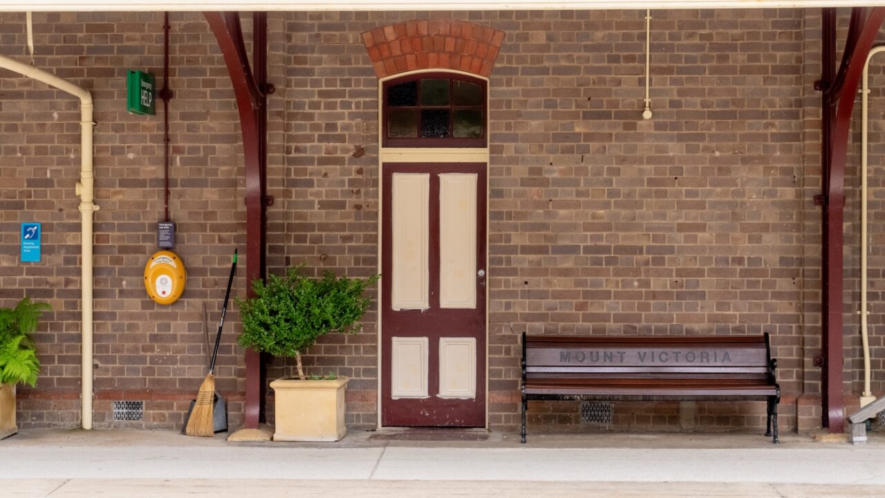 A brick wall with a white door, a bench labeled "Mount Victoria".