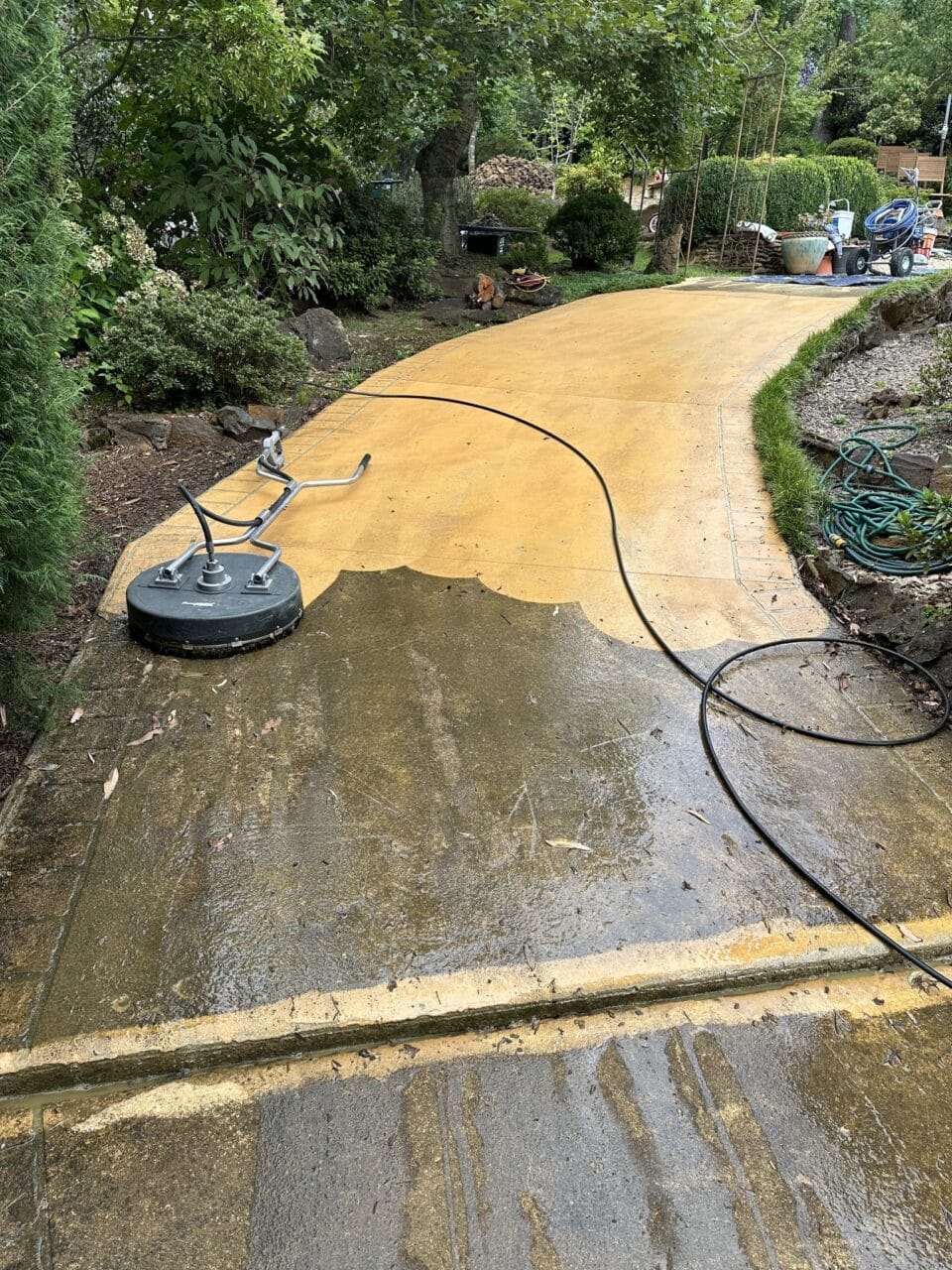 A dirty pathway partially cleaned by a pressure washing machine