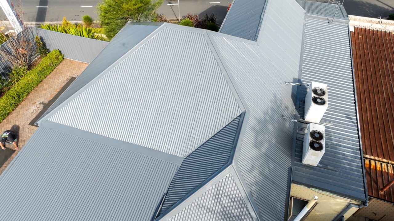 Aerial view of a gray corrugated metal roof with multiple slopes