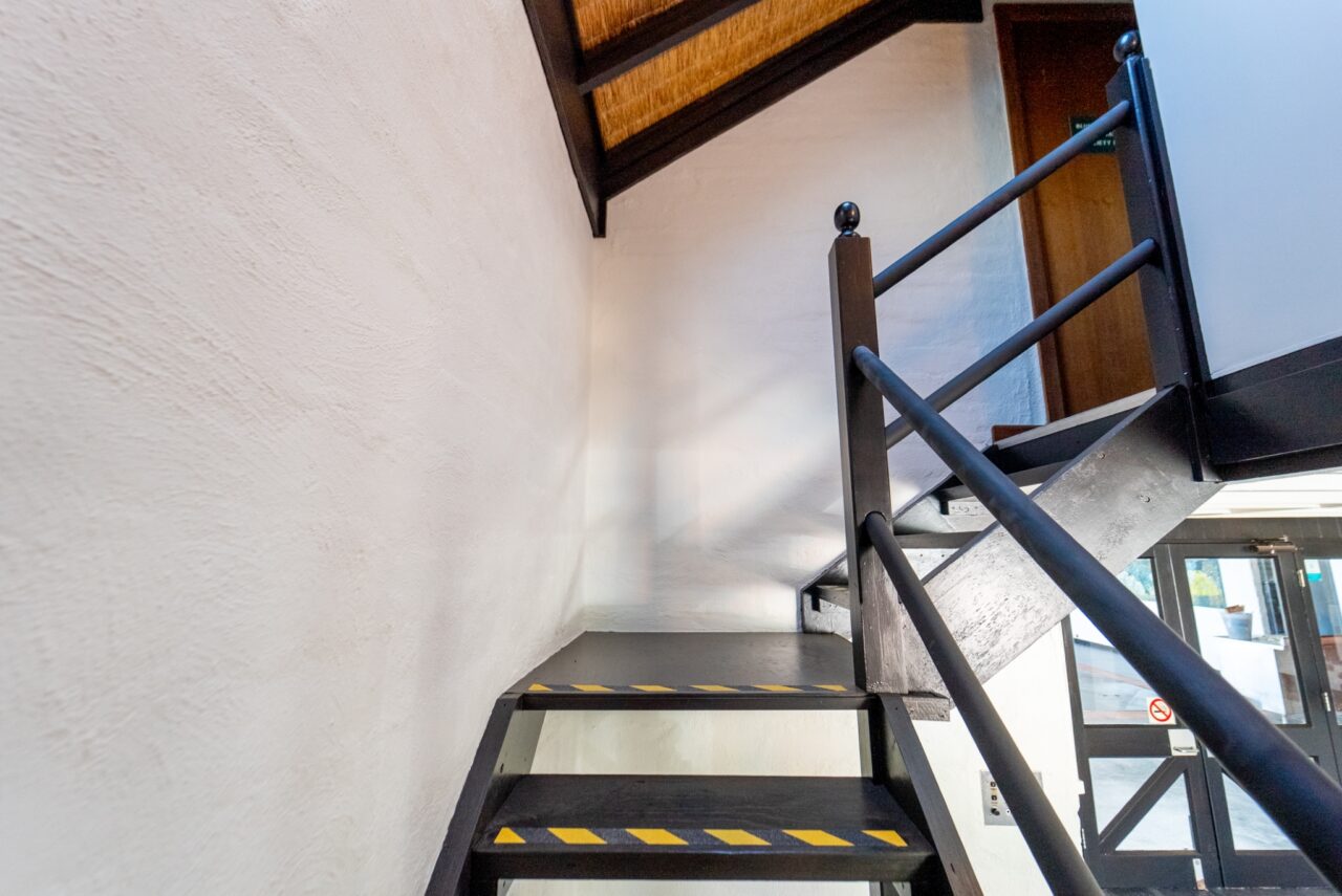 Black metal staircase with yellow safety stripes that leads to a loft.