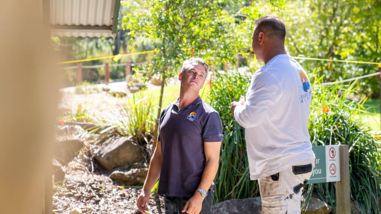 Two men in casual work attire are conversing outdoors at Wentworth Falls Lookout