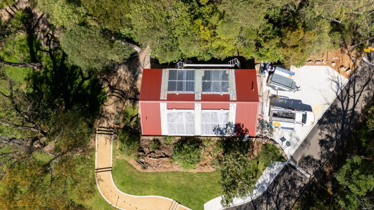 Aerial view of a red-roofed building surrounded by trees with a parking area