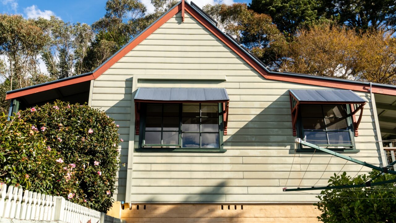 Bullaburra house in a charming single-story home with light green siding and two awnings.