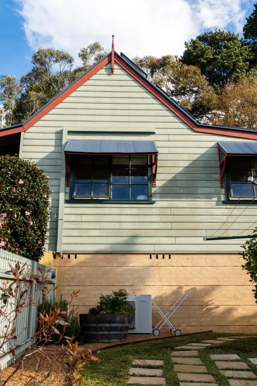 Bullaburra house boasts green siding with red trim with two awning windows.