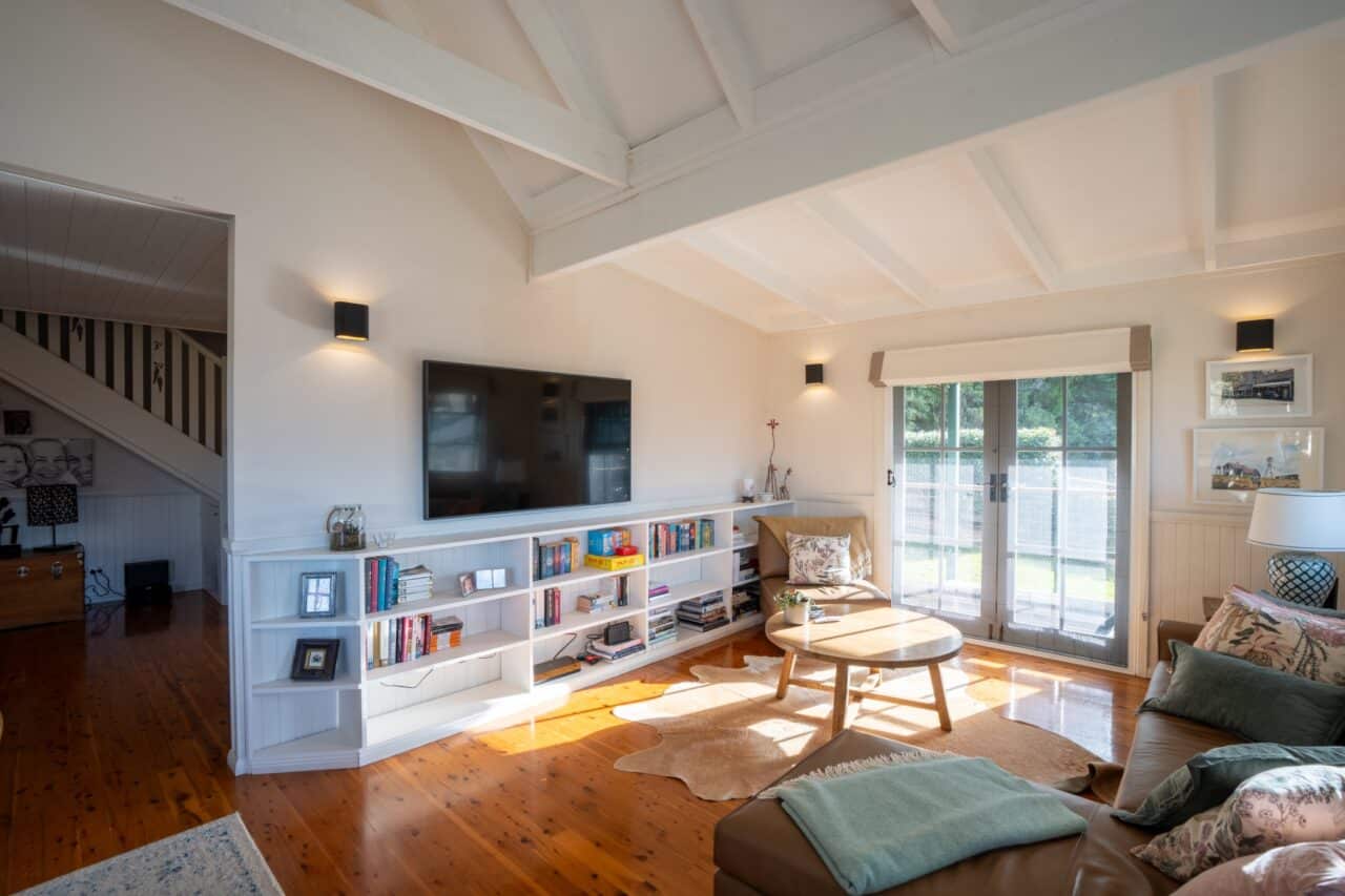 Bright living room at bullaburra house featuring a large tv, a bookshelf, and round wooden table.