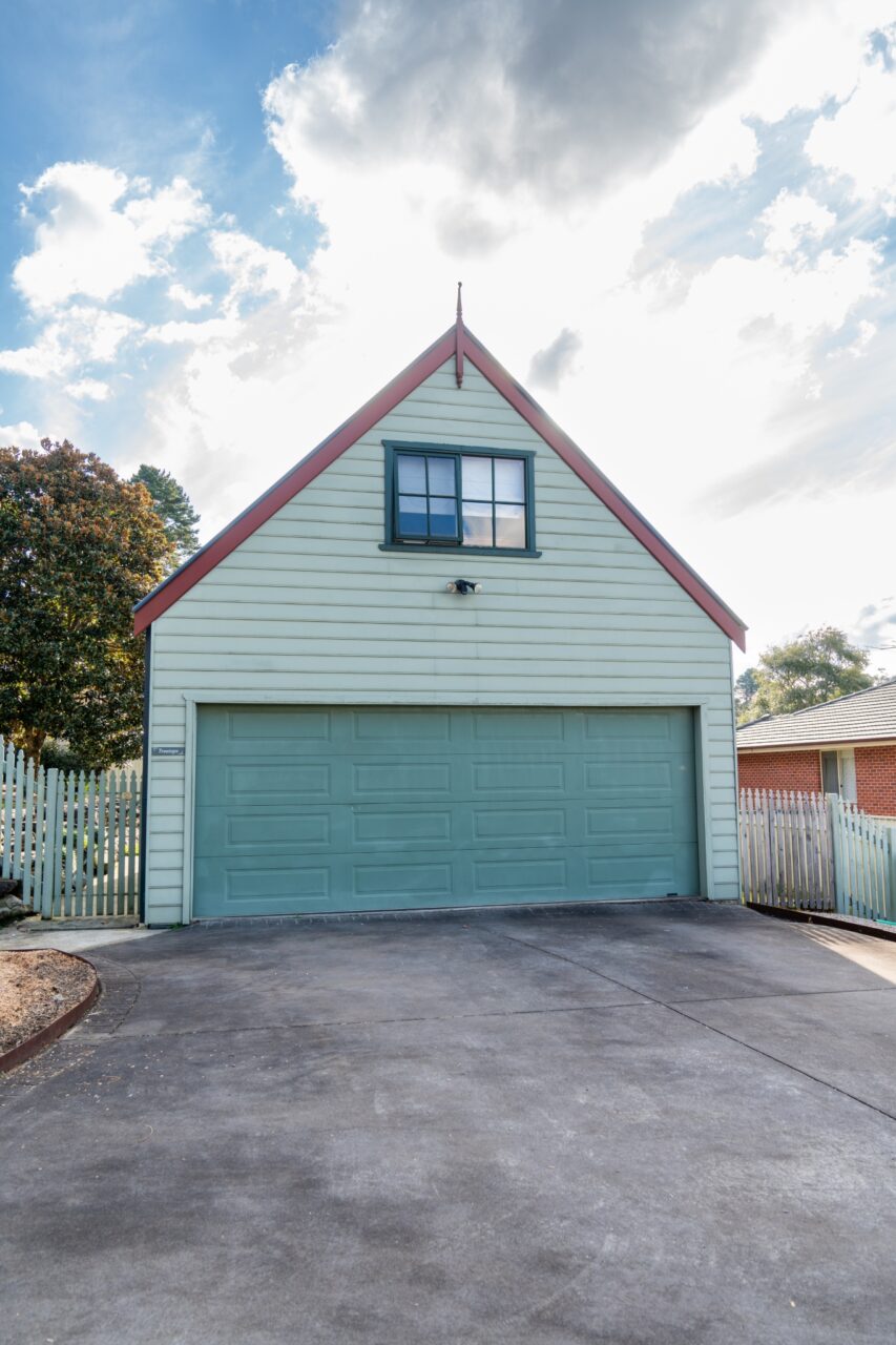 Front view of a green garage, reminiscent of bullaburra house, with a triangular roof.
