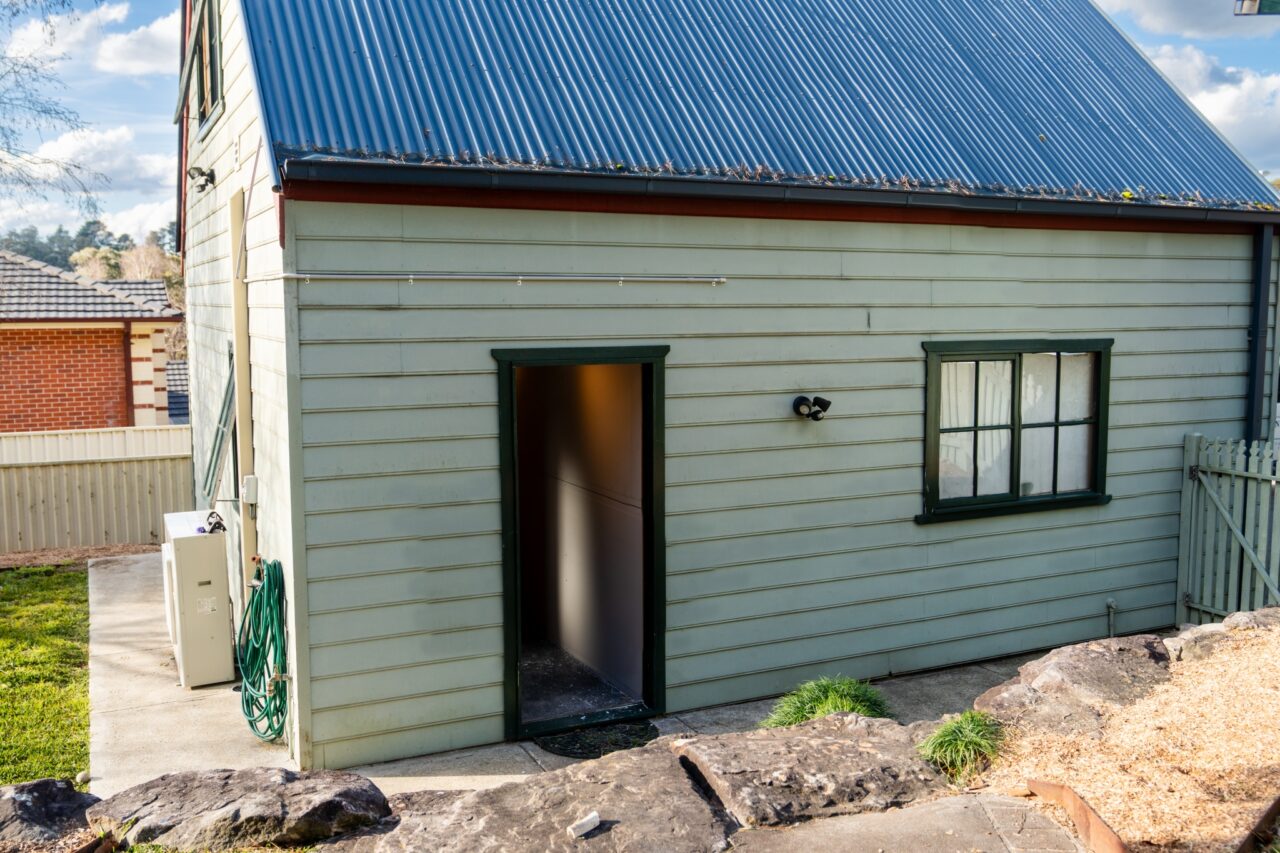 Exterior view of bullaburra house, a small, light green building.