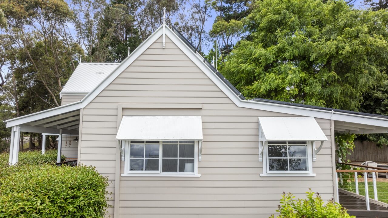 a charming beige bullaburra house, featuring two white awning windows