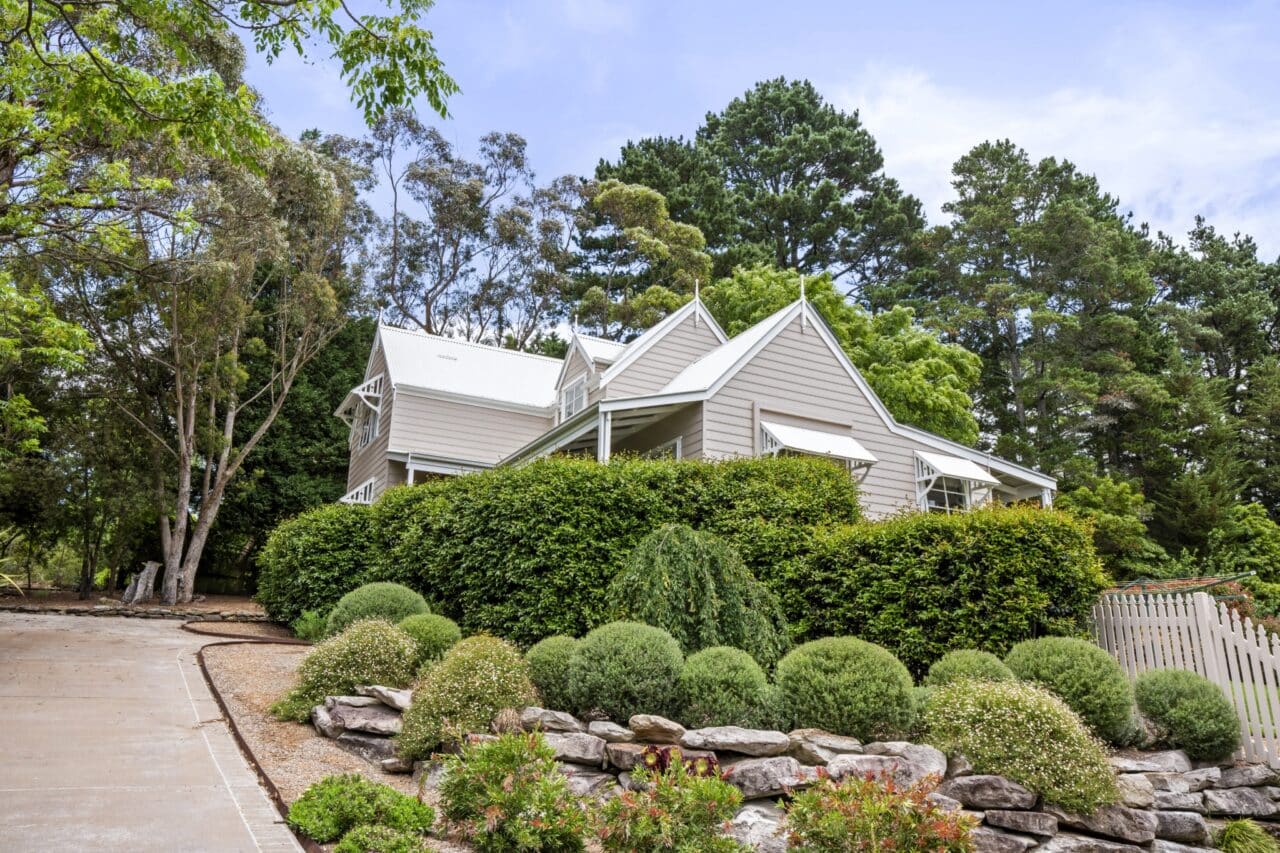 suburban home with a gray exterior and enveloped by lush greenery, including trees