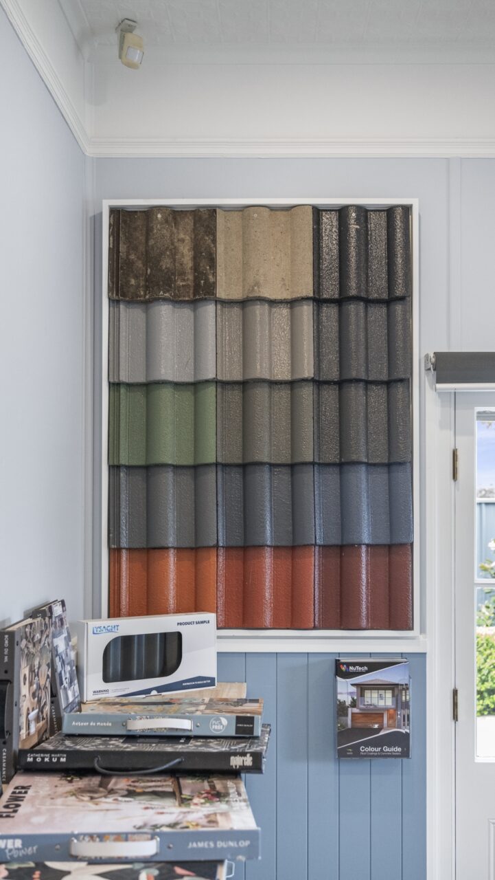 Display of various colored roof tiles on a wall, featuring brochures and samples.