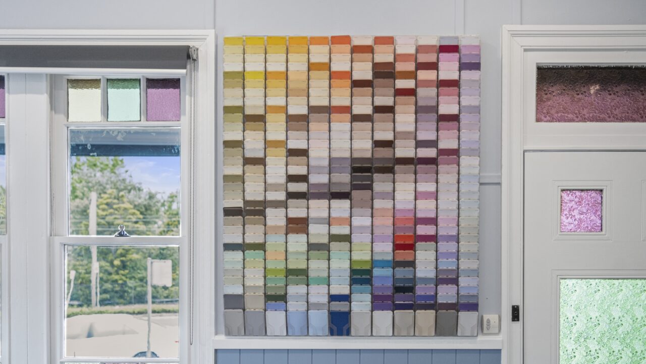 Wall display of various colored paint swatches arranged in a grid pattern.