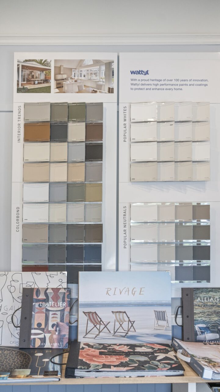 Display of paint color samples on a wall with brochures on a table.