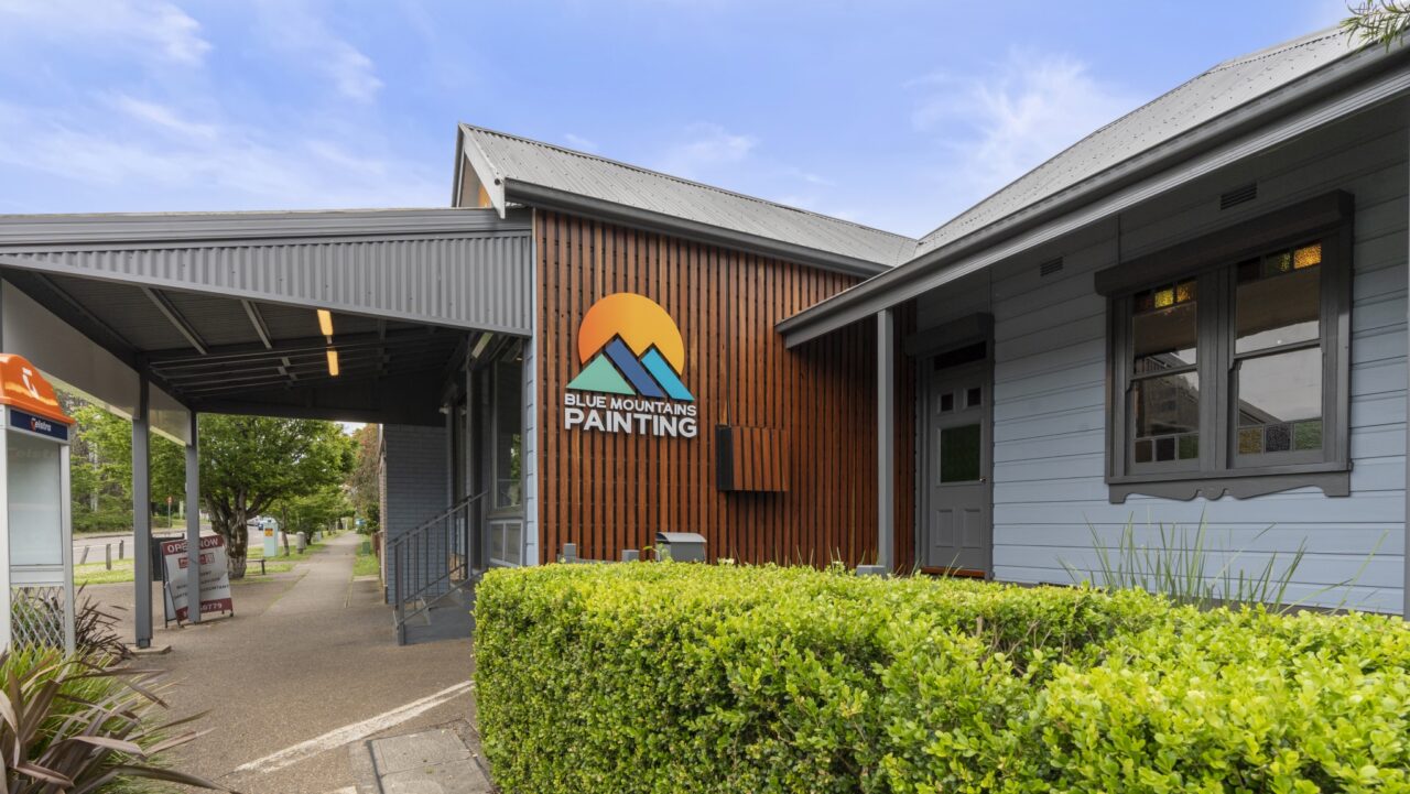 exterior of the building boasting a "blue mountains painting" sign, with wooden and grey paneling