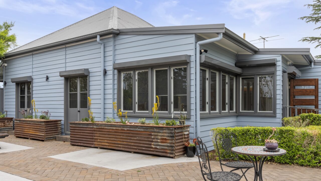 light blue modern bullaburra house with large windows, surrounded by planter boxes