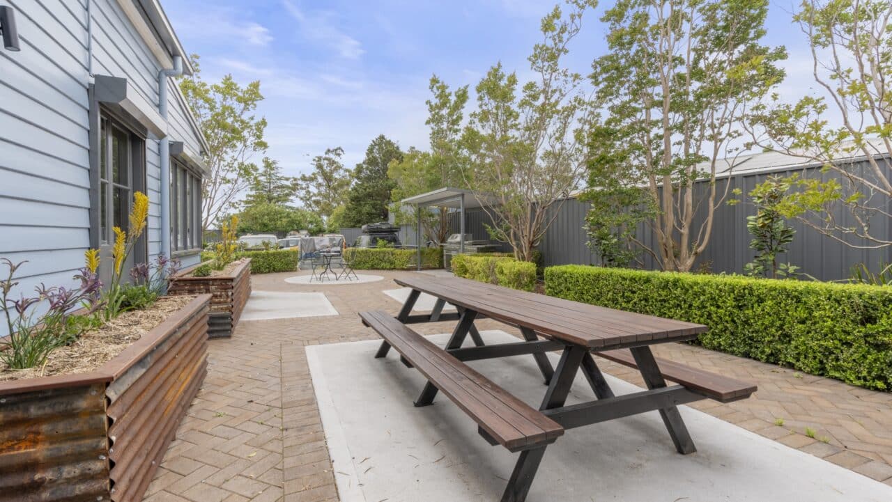 nestled within the bullaburra house grounds featuring wooden picnic table set on a paved path