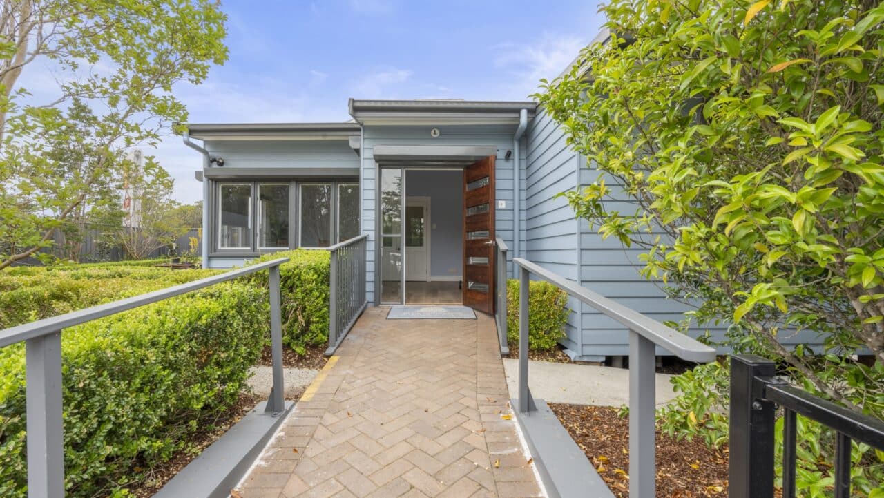 entrance of bullaburra house featuring a modern blue facade with an open wooden door