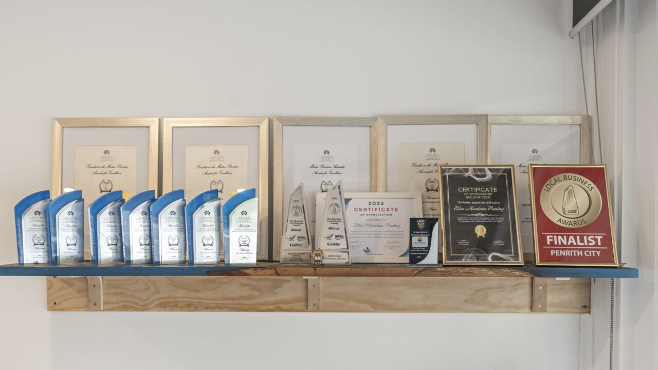 a shelf at bullaburra house proudly displays framed certificates, plaques, and numerous trophies
