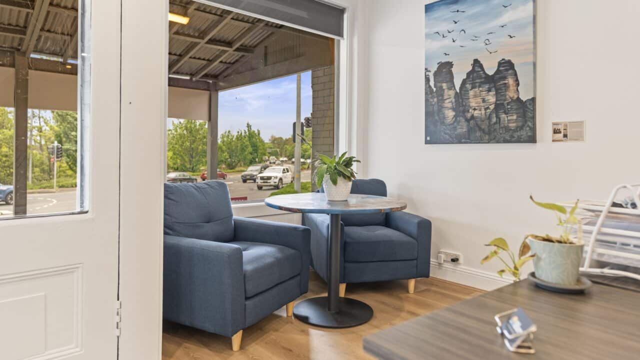 the cozy waiting area at bullaburra house features two blue armchairs and a round table