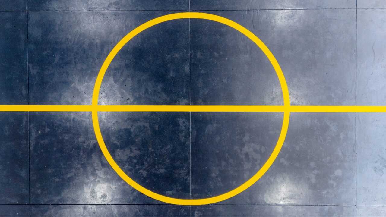 a yellow circle with a horizontal line through the center, reminiscent of precise line marking, is painted on a dark, textured surface.