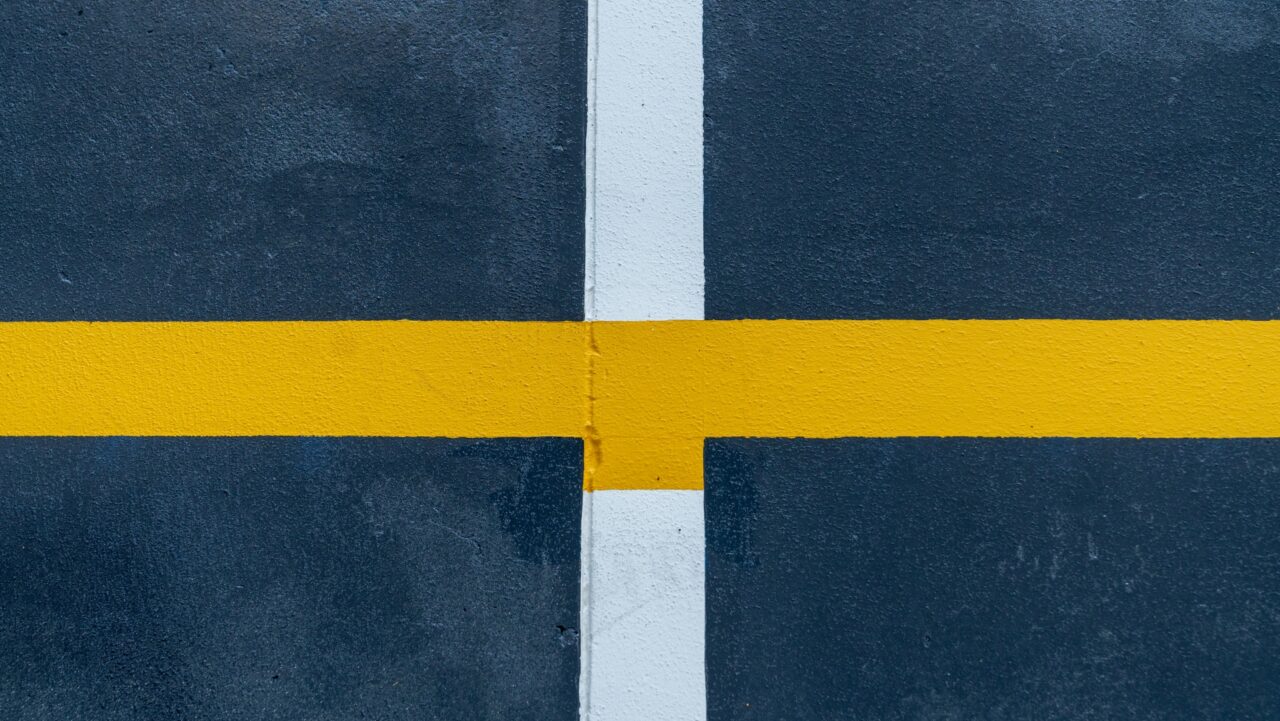 a yellow line marking intersects a white line on the dark pavement background near springwood high school.