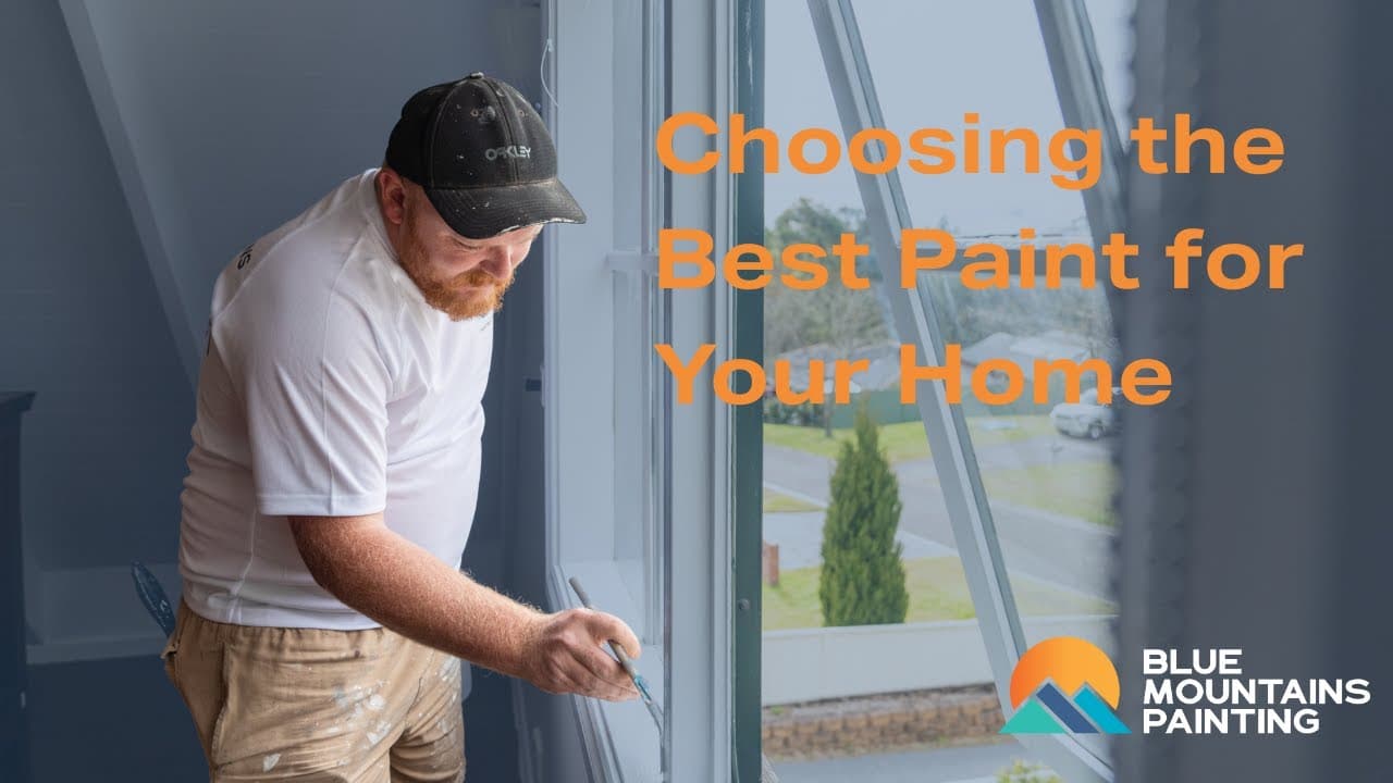 A man painting a window frame inside a house, with the text "Choosing the Best Paint for Your Home" and the Blue Mountains Painting logo in the corner, highlights tips for choosing paint that enhances your space.